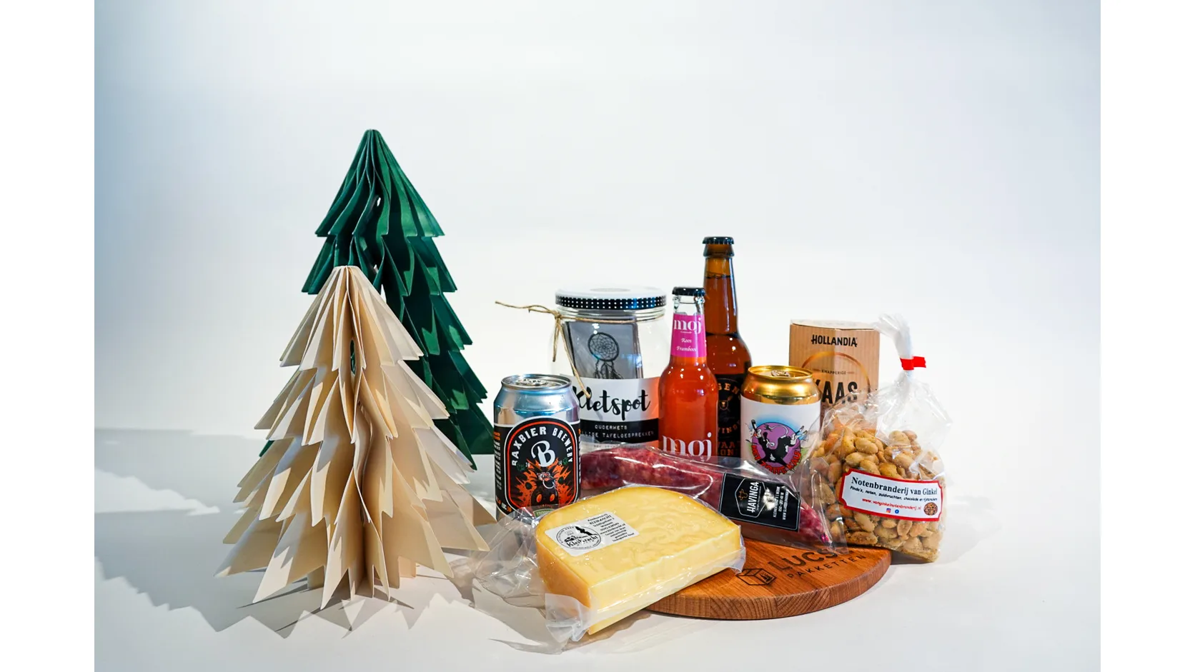 Kerstpakket met kaas, bier, droge worst, noten en jam op een houten plank